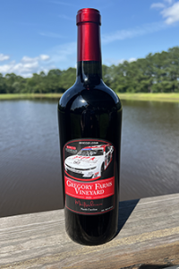 Gregory Farms Vineyard limited edition red wine with race car label set against a scenic pond view in Currie NC.