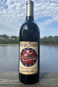 Gregory Farms Vineyard 2nd Amendment sweet red wine bottle displayed on a wooden deck overlooking the vineyard pond in Currie NC.