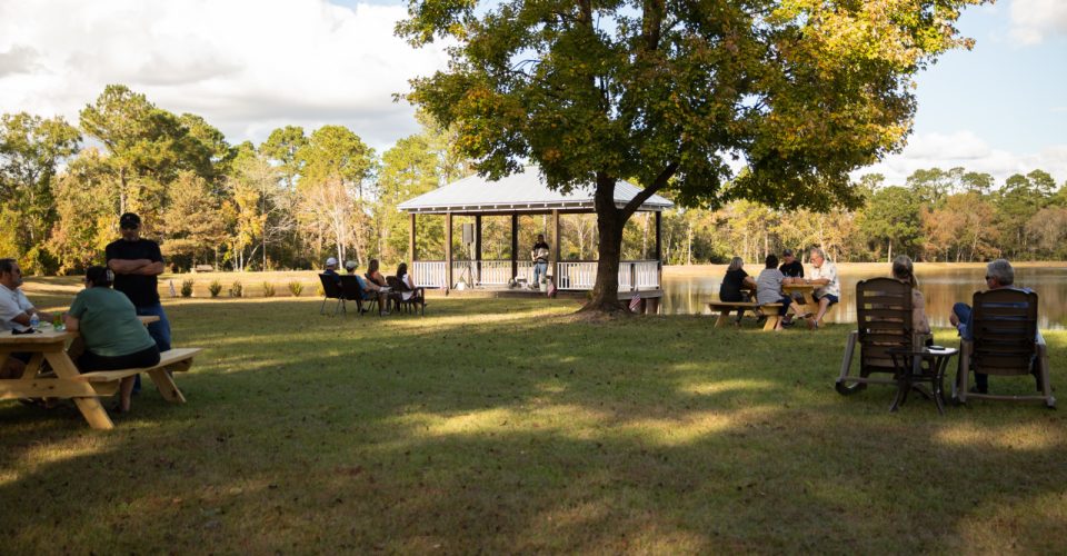 Live music by the gazebo at Gregory Farms Vineyard in Currie NC with guests seated around the pond.
